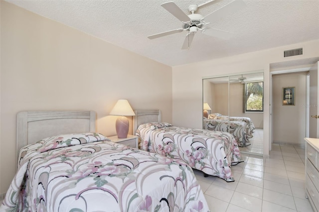 tiled bedroom with ceiling fan, a closet, and a textured ceiling