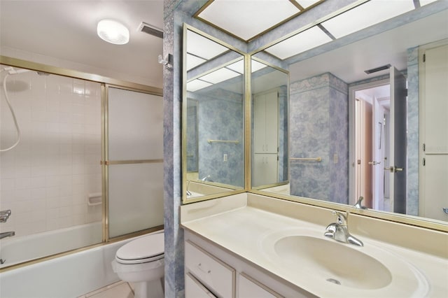 full bathroom featuring bath / shower combo with glass door, vanity, and toilet