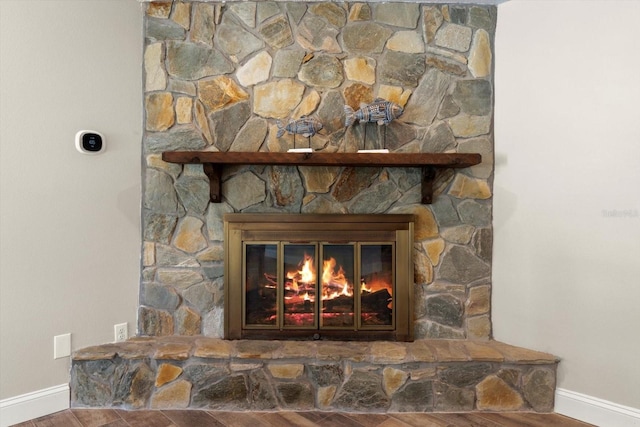 details featuring a stone fireplace and wood-type flooring