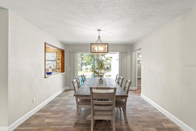 dining area with an inviting chandelier, plenty of natural light, dark hardwood / wood-style floors, and a textured ceiling