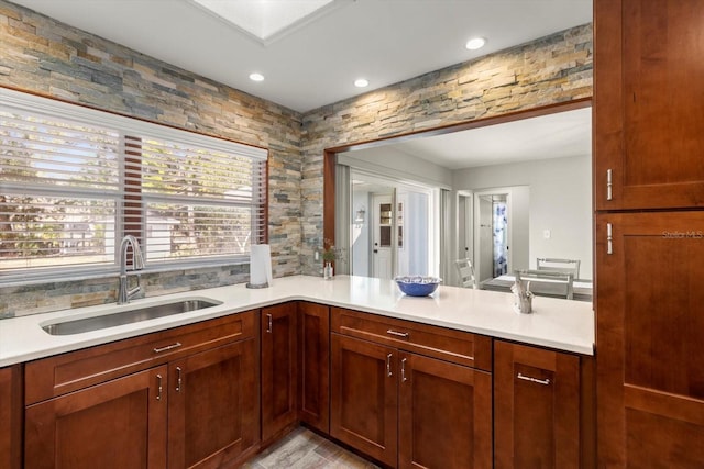 kitchen featuring sink, a skylight, kitchen peninsula, and light wood-type flooring