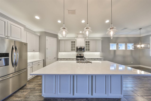 kitchen featuring decorative light fixtures, sink, white cabinets, a large island, and stainless steel appliances