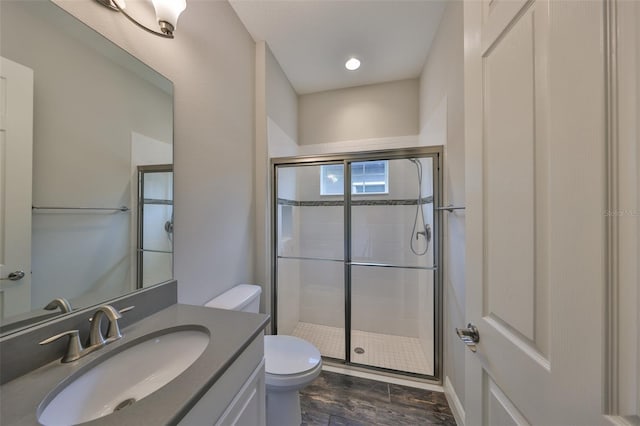 bathroom with a shower with door, vanity, and toilet