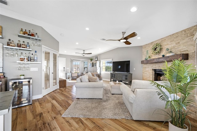 living room featuring french doors, bar, wood-type flooring, vaulted ceiling, and beverage cooler