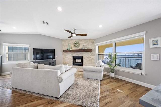 living room featuring wood-type flooring, vaulted ceiling, ceiling fan, and a fireplace