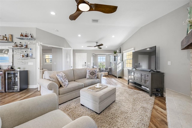 living room featuring lofted ceiling, bar area, ceiling fan, beverage cooler, and light hardwood / wood-style floors