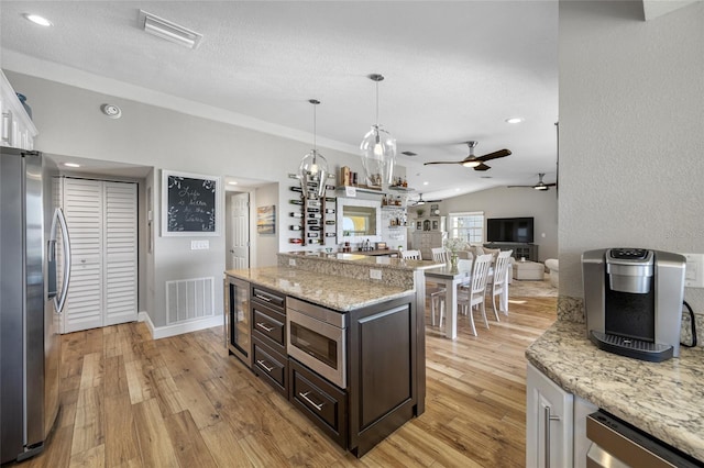 kitchen with light stone counters, dark brown cabinets, white cabinets, and appliances with stainless steel finishes