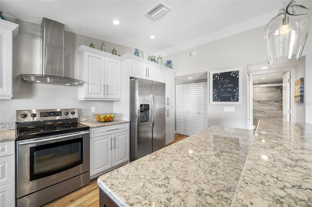 kitchen featuring pendant lighting, white cabinets, stainless steel appliances, light stone countertops, and wall chimney exhaust hood