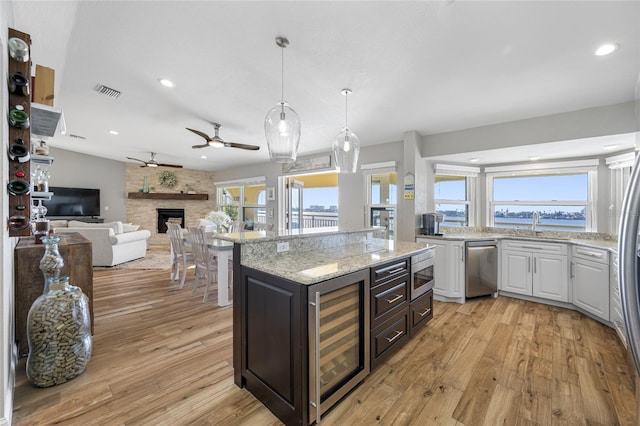 kitchen with appliances with stainless steel finishes, white cabinetry, a center island, a healthy amount of sunlight, and beverage cooler