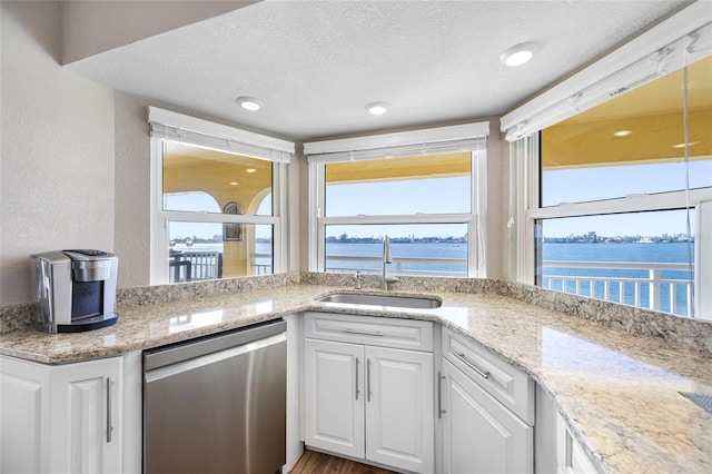 kitchen with sink, white cabinetry, a water view, a textured ceiling, and stainless steel dishwasher