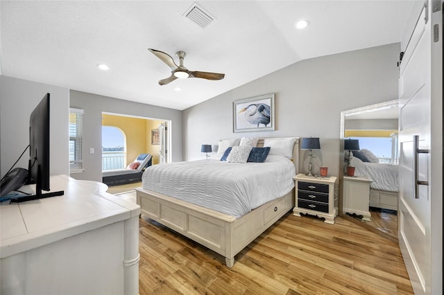 bedroom featuring multiple windows, vaulted ceiling, and light hardwood / wood-style floors