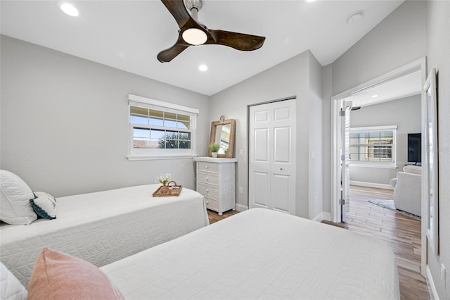 bedroom featuring wood-type flooring, lofted ceiling, ceiling fan, and a closet