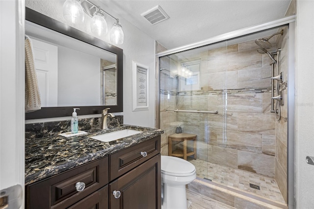 bathroom with a shower with door, vanity, and toilet