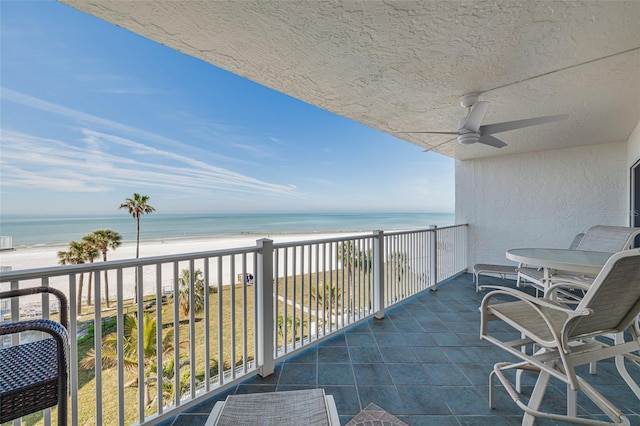 balcony with a water view, ceiling fan, and a view of the beach