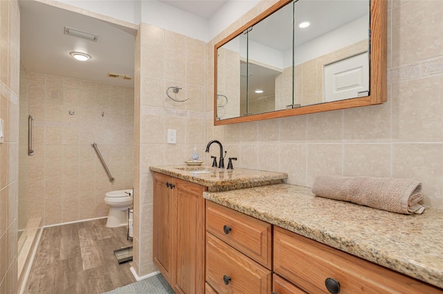 bathroom with vanity, toilet, wood-type flooring, and tile walls