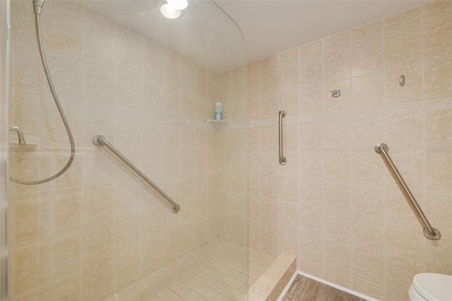 bathroom featuring tiled shower and toilet