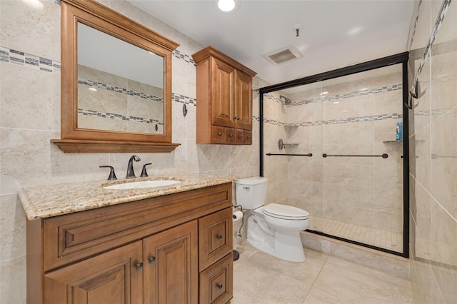 bathroom with toilet, tile walls, vanity, a shower with door, and tile patterned flooring