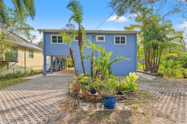 coastal home with driveway, a carport, and fence