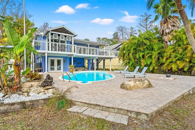 pool with french doors, a patio, and a deck