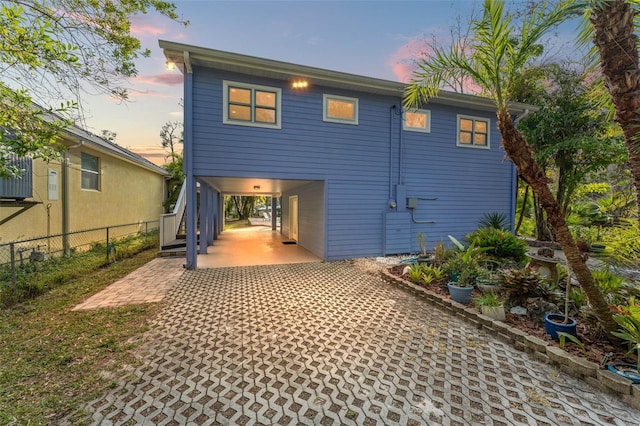 back house at dusk featuring a carport