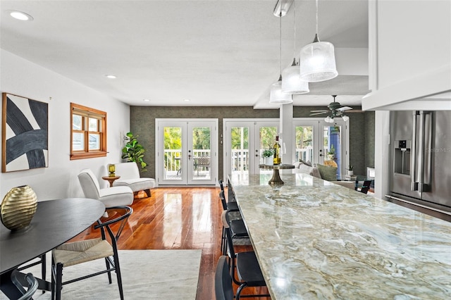 kitchen with light stone counters, french doors, wood-type flooring, and a wealth of natural light