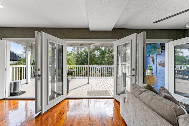 doorway featuring a textured ceiling, hardwood / wood-style flooring, a wealth of natural light, and wallpapered walls