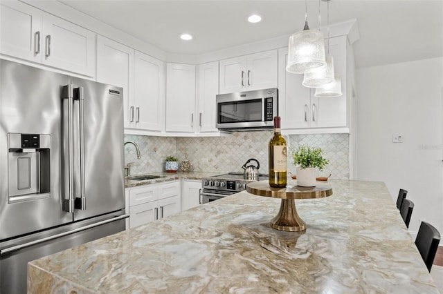 kitchen featuring stainless steel appliances, a sink, white cabinets, backsplash, and light stone countertops