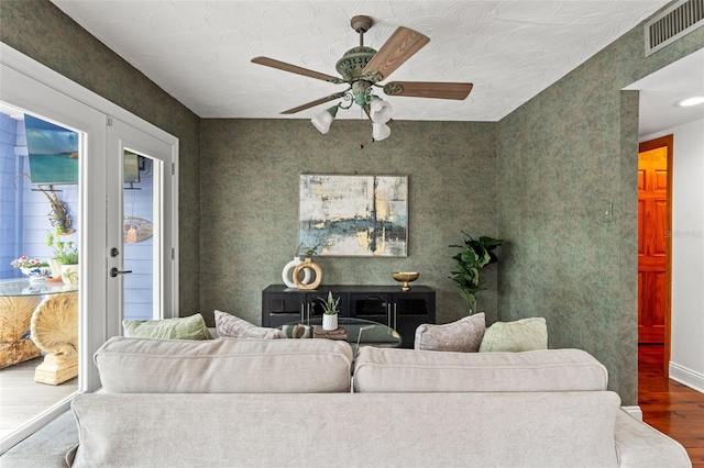 living area with a ceiling fan, visible vents, wood finished floors, and french doors