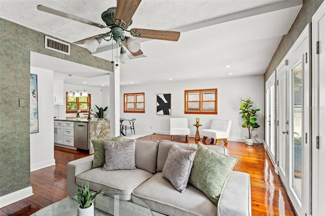 living area featuring a ceiling fan, visible vents, baseboards, and hardwood / wood-style flooring