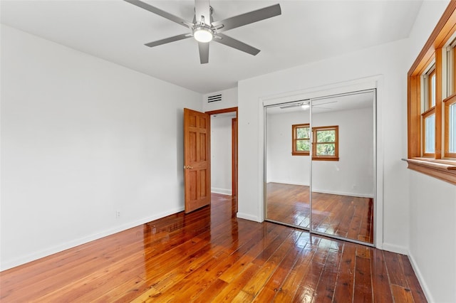 unfurnished bedroom with baseboards, a closet, visible vents, and hardwood / wood-style floors