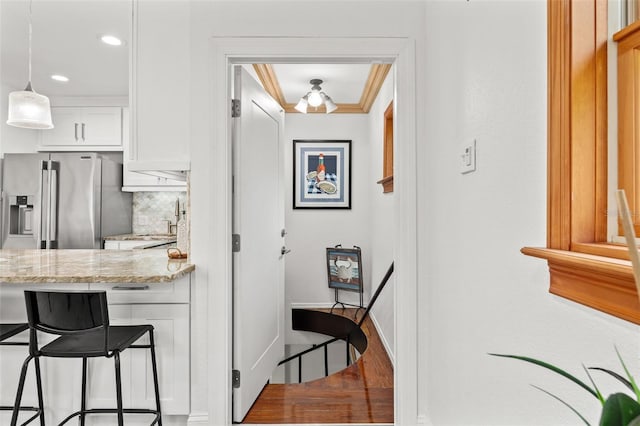 kitchen with light stone counters, white cabinetry, a kitchen breakfast bar, stainless steel refrigerator with ice dispenser, and tasteful backsplash