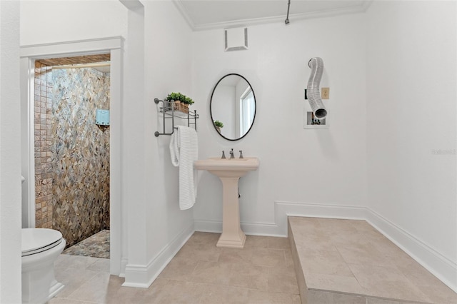 full bathroom with ornamental molding, tiled shower, toilet, and baseboards