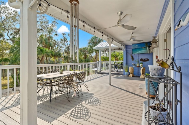 deck with outdoor dining space and a ceiling fan