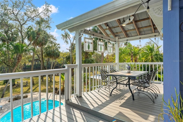 deck with outdoor dining space, an outdoor pool, and a gazebo