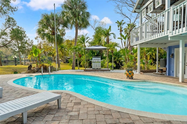 outdoor pool with a patio area and a grill