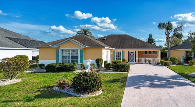 ranch-style home featuring covered porch, a front lawn, decorative driveway, and stucco siding