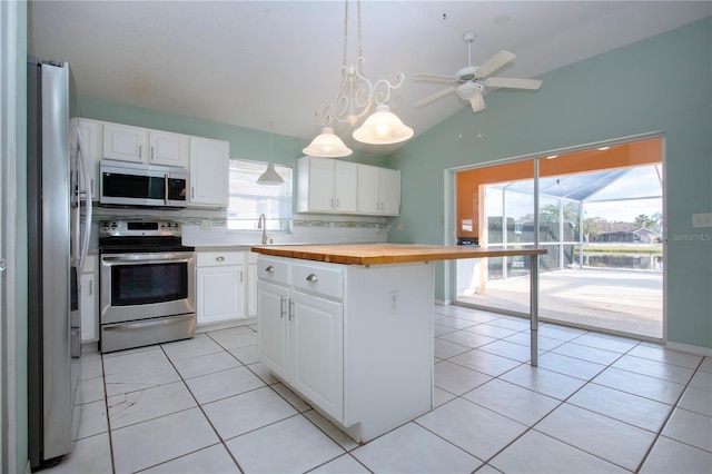 kitchen featuring butcher block counters, white cabinetry, stainless steel appliances, and a center island