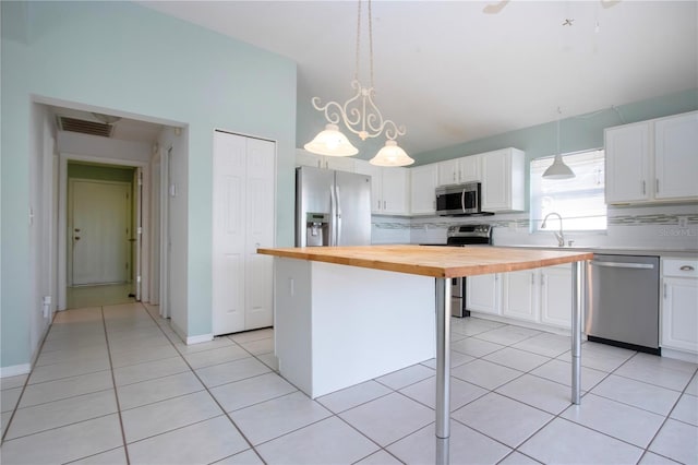 kitchen featuring stainless steel appliances, wood counters, visible vents, a kitchen island, and white cabinetry