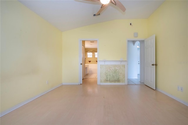 empty room featuring light wood finished floors, visible vents, a ceiling fan, vaulted ceiling, and baseboards