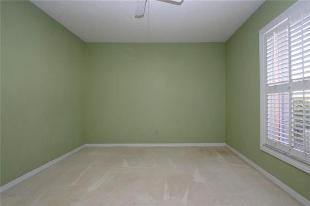 unfurnished room featuring a ceiling fan, light carpet, a textured ceiling, and baseboards