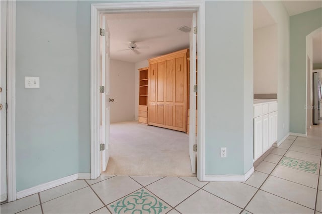 hall with light carpet, baseboards, and light tile patterned floors