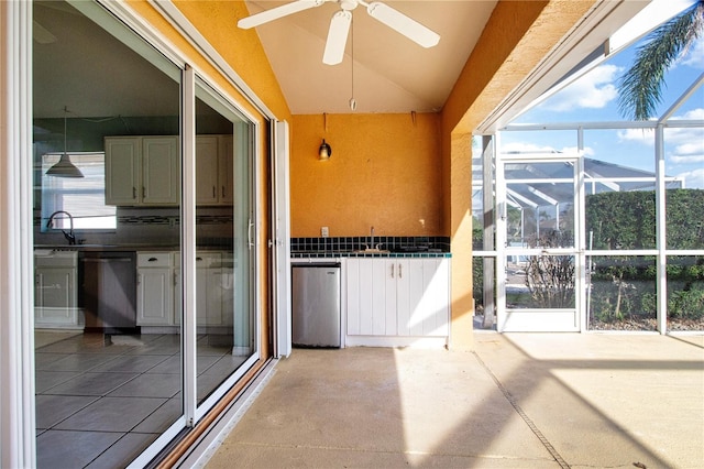 unfurnished sunroom with vaulted ceiling, a sink, and a ceiling fan