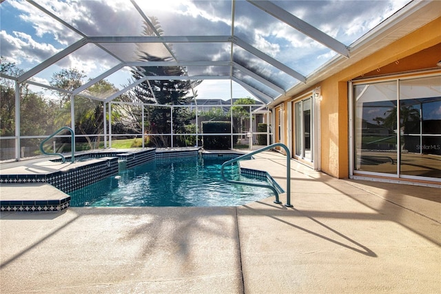 pool with glass enclosure, a patio area, and an in ground hot tub