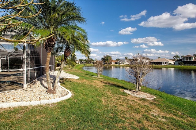 view of yard with glass enclosure, a water view, and a residential view