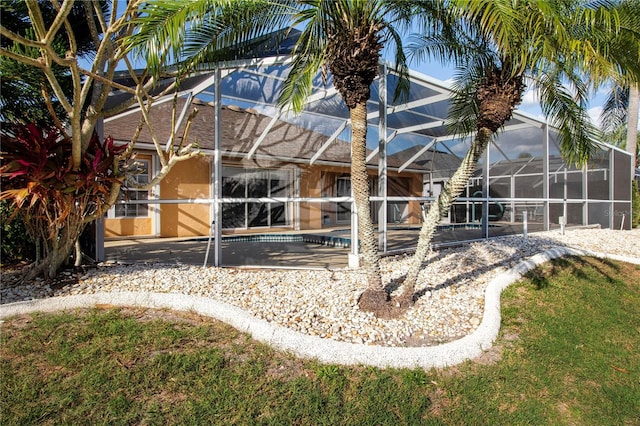 back of house with a lawn and a lanai