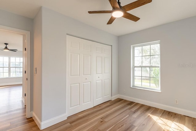 unfurnished bedroom featuring ceiling fan, light hardwood / wood-style floors, and a closet