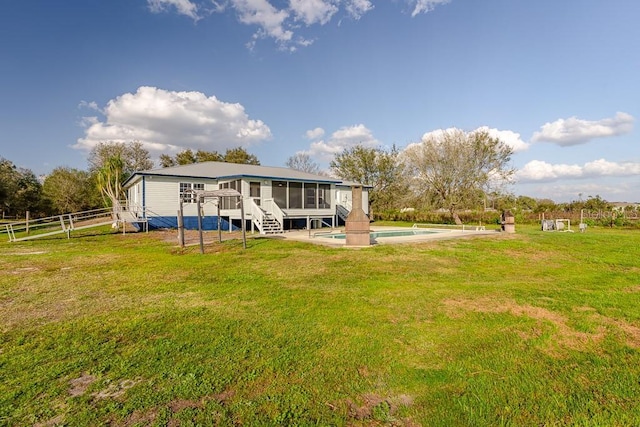 back of house featuring a swimming pool side deck, a sunroom, and a lawn