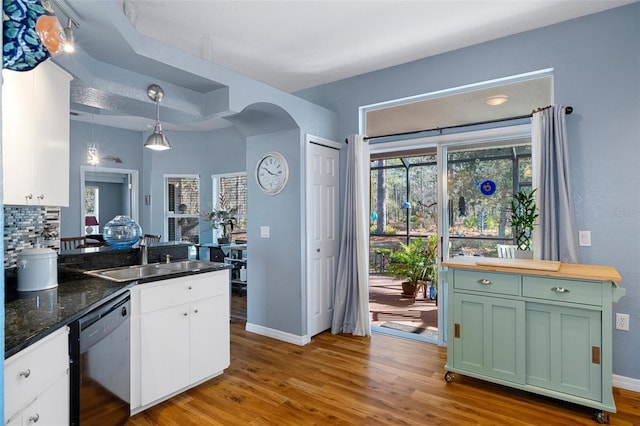 kitchen with sink, dishwasher, hanging light fixtures, green cabinetry, and light wood-type flooring