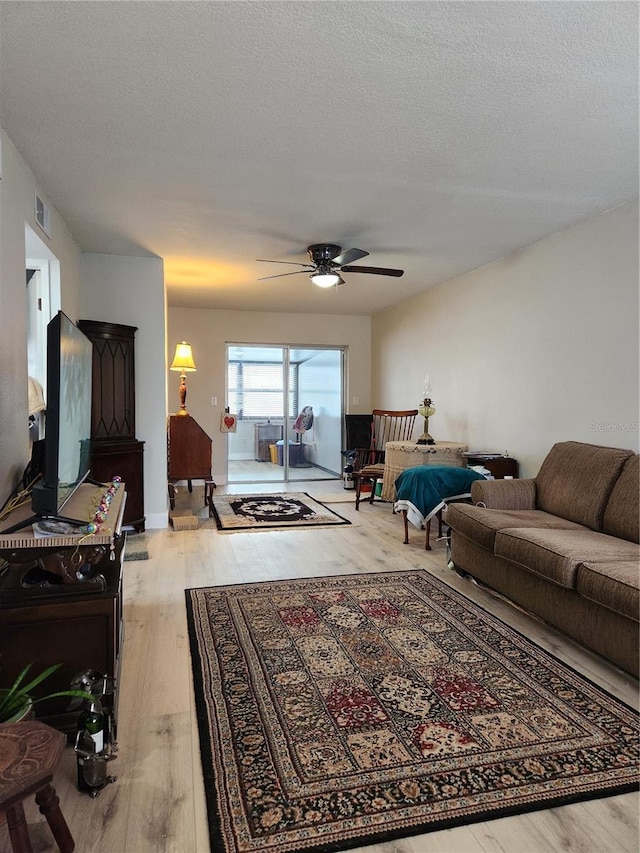 living room with ceiling fan, light hardwood / wood-style floors, and a textured ceiling