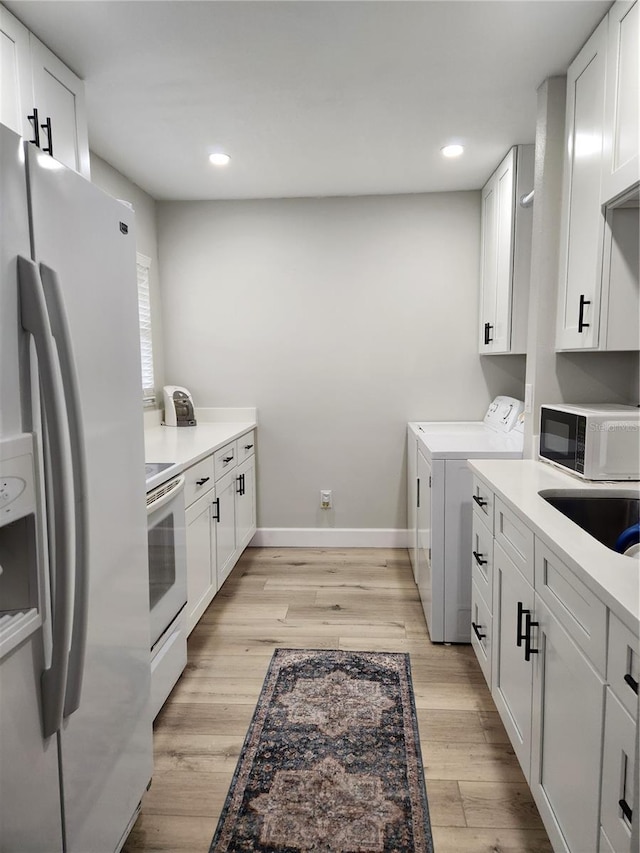 washroom featuring washing machine and dryer, sink, and light hardwood / wood-style flooring